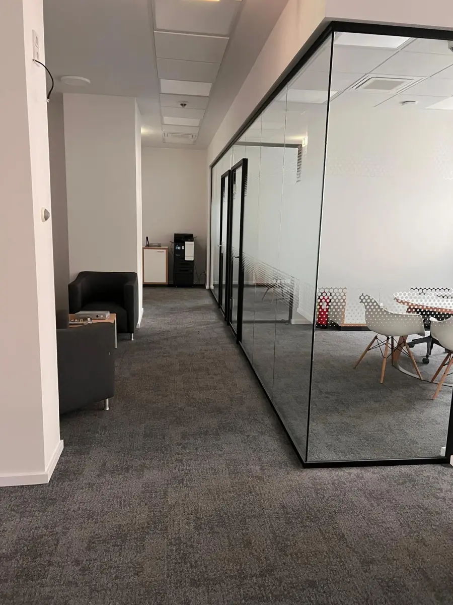 Modernisierte Bürofläche mit grauem Teppichboden und verglasten Besprechungsräumen