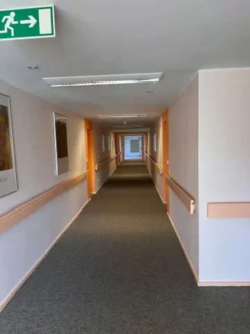Sanierter Flur mit neu verlegtem dunklem Teppichboden